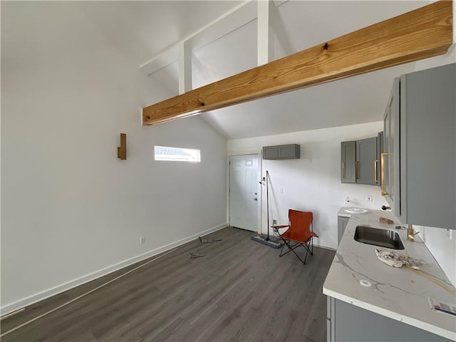 kitchen featuring dark wood-type flooring, sink, lofted ceiling with beams, and gray cabinetry