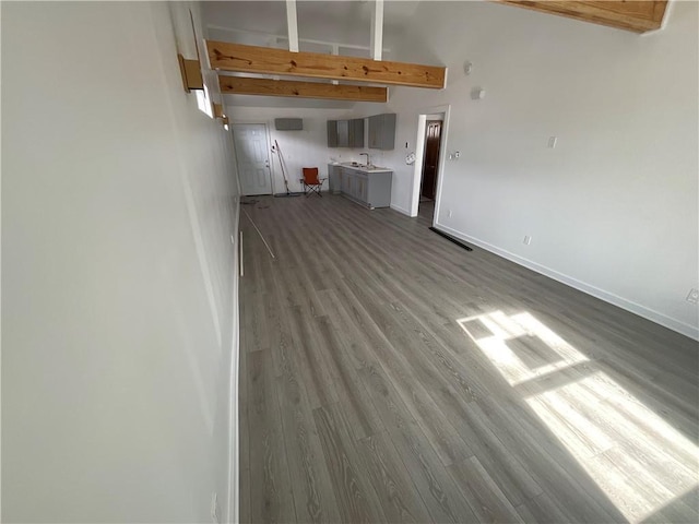 unfurnished living room with beamed ceiling, high vaulted ceiling, and light wood-type flooring