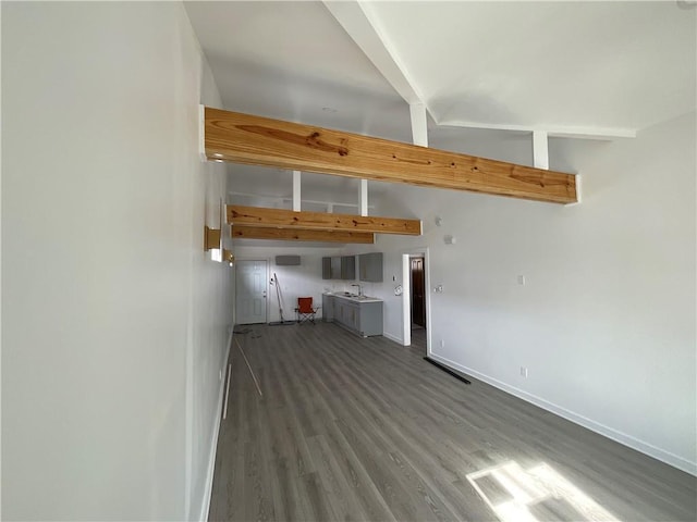 unfurnished living room featuring hardwood / wood-style flooring and beamed ceiling