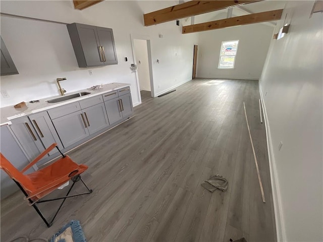 kitchen featuring lofted ceiling with beams, light hardwood / wood-style floors, sink, and gray cabinetry