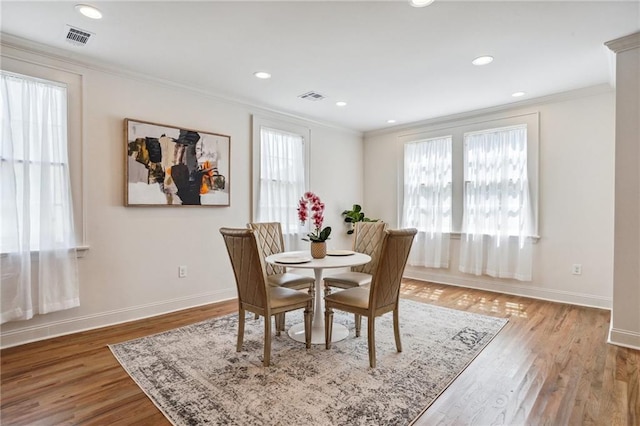 dining area with wood-type flooring and ornamental molding