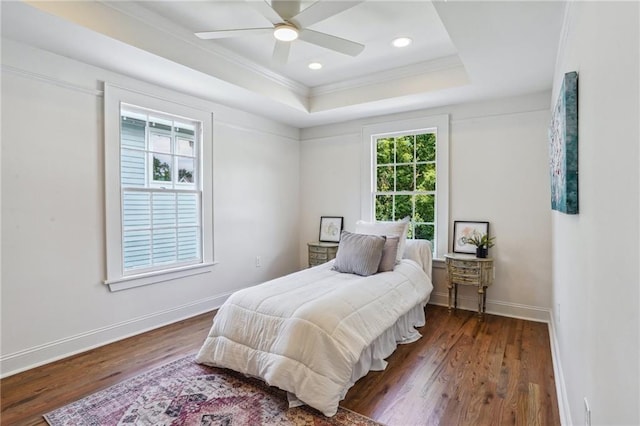 bedroom with ceiling fan, ornamental molding, a tray ceiling, and dark hardwood / wood-style flooring