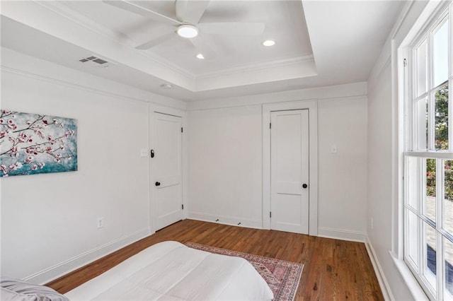 bedroom with crown molding, ceiling fan, hardwood / wood-style floors, access to exterior, and a tray ceiling