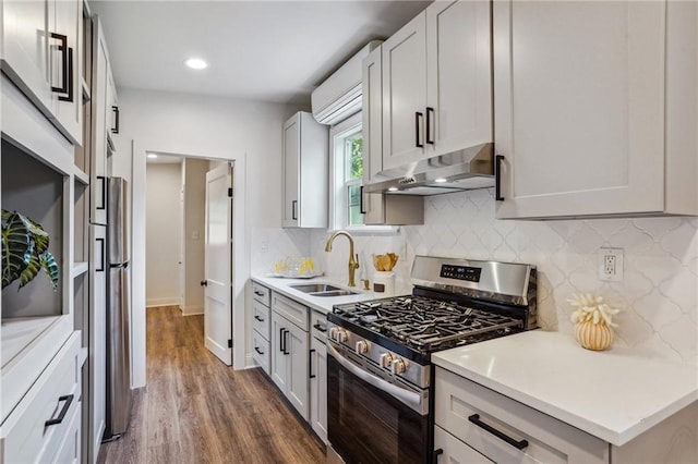 kitchen with stainless steel range with gas cooktop, dark hardwood / wood-style floors, sink, white cabinets, and backsplash