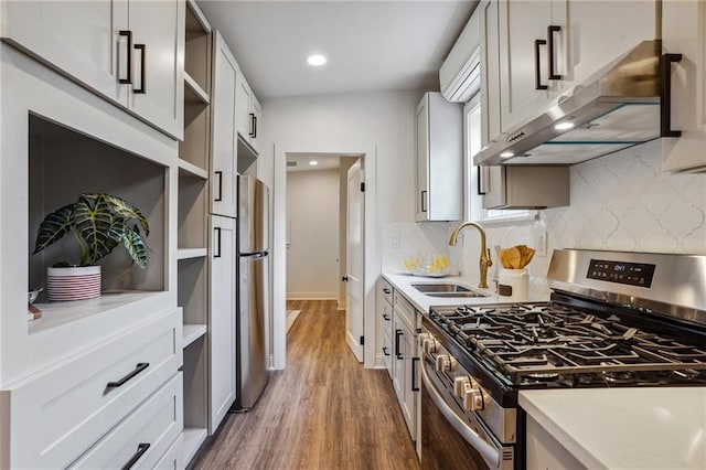 kitchen with sink, appliances with stainless steel finishes, backsplash, white cabinets, and dark hardwood / wood-style flooring