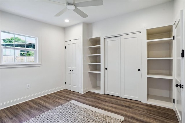 unfurnished bedroom featuring dark hardwood / wood-style flooring, two closets, and ceiling fan