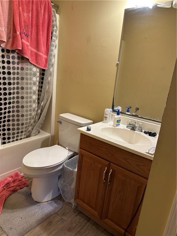 full bathroom featuring vanity, hardwood / wood-style flooring, shower / bath combination with curtain, and toilet