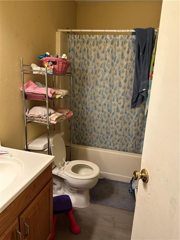 full bathroom with shower / bathtub combination with curtain, vanity, wood-type flooring, and toilet