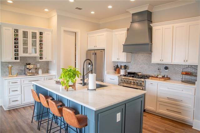 kitchen with white cabinetry, premium range hood, a kitchen island with sink, and premium appliances