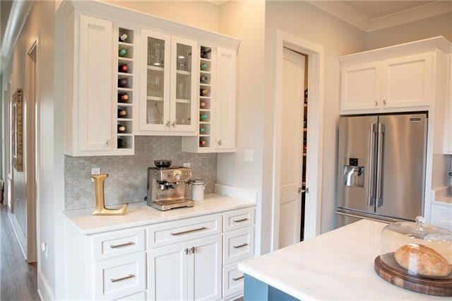 kitchen featuring crown molding, high end fridge, white cabinets, and backsplash