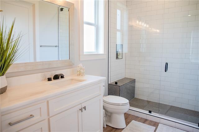 bathroom with hardwood / wood-style flooring, vanity, an enclosed shower, and toilet