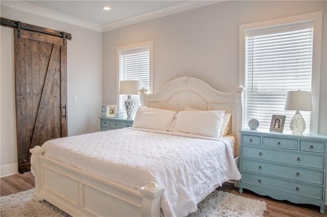 bedroom with crown molding, a barn door, and light hardwood / wood-style flooring