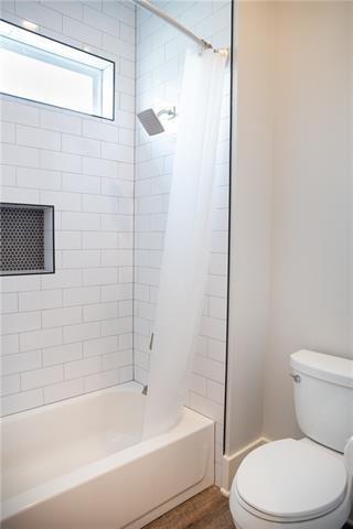 bathroom with shower / tub combo with curtain, hardwood / wood-style flooring, and toilet