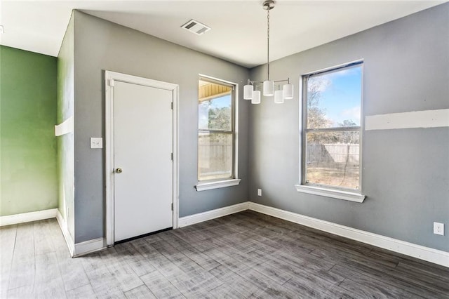 unfurnished dining area featuring hardwood / wood-style flooring and an inviting chandelier