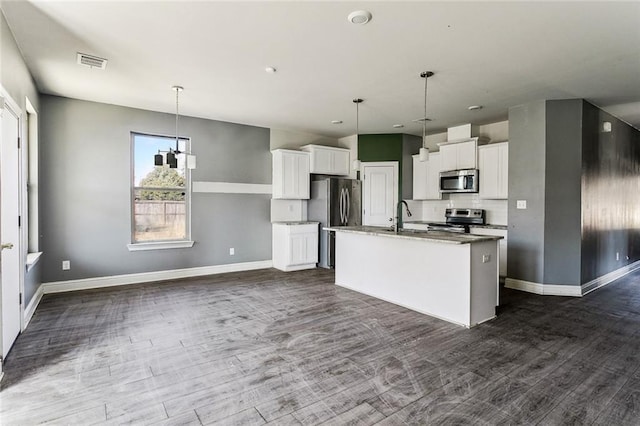 kitchen with a center island with sink, appliances with stainless steel finishes, dark hardwood / wood-style flooring, pendant lighting, and white cabinets