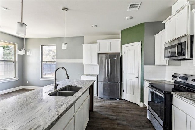 kitchen with pendant lighting, sink, white cabinetry, stainless steel appliances, and light stone countertops