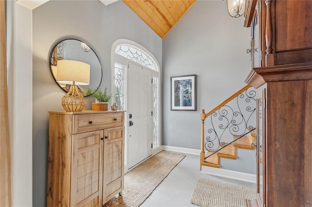 foyer entrance featuring wood ceiling, stairs, baseboards, and vaulted ceiling