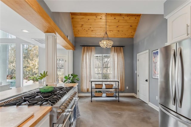 kitchen with lofted ceiling, baseboards, white cabinets, hanging light fixtures, and appliances with stainless steel finishes