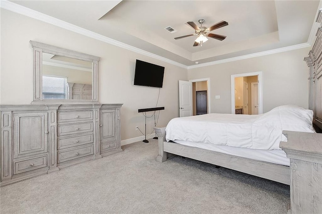 bedroom featuring ceiling fan, ensuite bathroom, ornamental molding, light colored carpet, and a raised ceiling