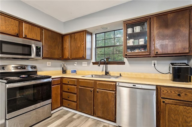 kitchen with stainless steel appliances, sink, and light wood-type flooring