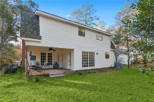 back of property with ceiling fan, a deck, and a lawn