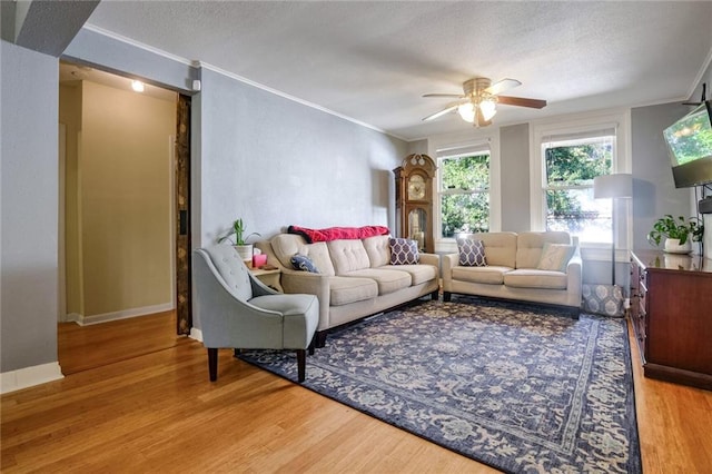 living room with wood-type flooring, ornamental molding, and ceiling fan