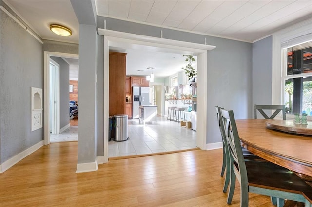 dining space with crown molding and light hardwood / wood-style floors