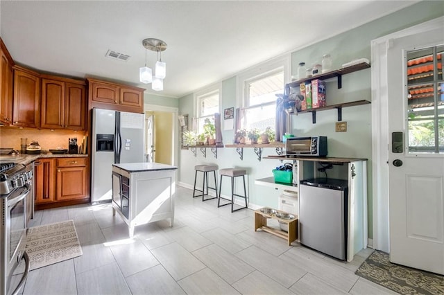 kitchen with a kitchen bar, a kitchen island, pendant lighting, stainless steel appliances, and backsplash