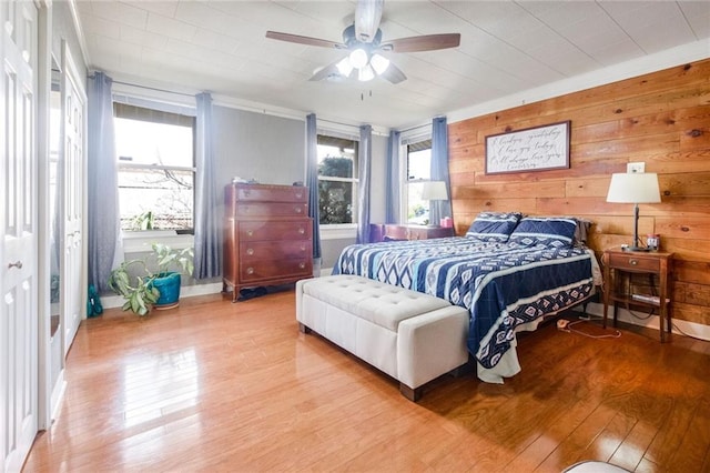 bedroom featuring wood walls, ceiling fan, and light hardwood / wood-style flooring