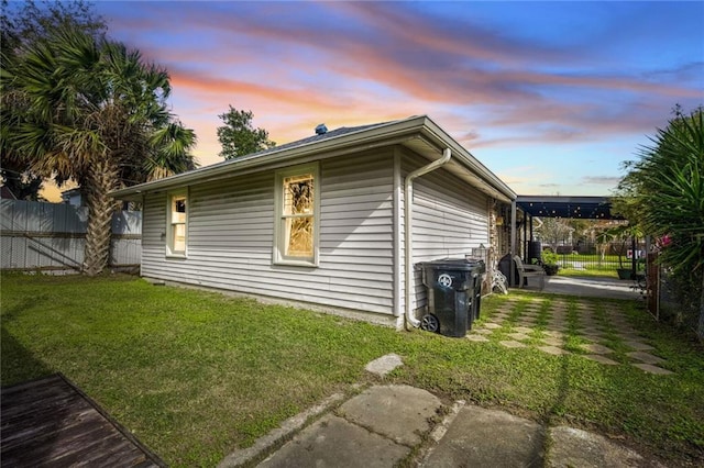 property exterior at dusk featuring a lawn