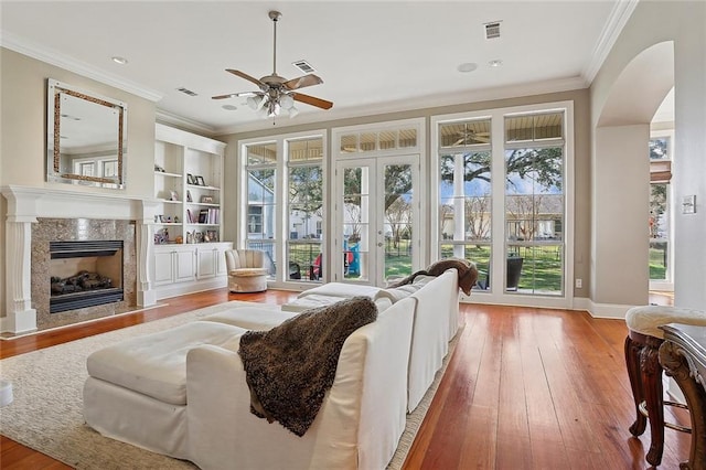 sunroom with french doors, ceiling fan, and a high end fireplace