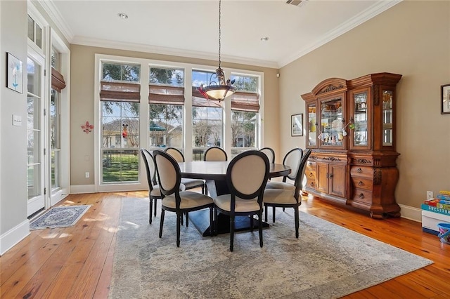 dining space with hardwood / wood-style floors, crown molding, and a wealth of natural light