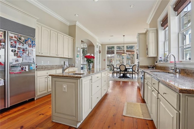 kitchen featuring stainless steel appliances, a kitchen island, hanging light fixtures, and sink