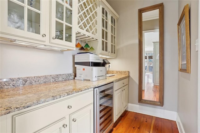 kitchen featuring wine cooler, light stone counters, light hardwood / wood-style flooring, and white cabinets