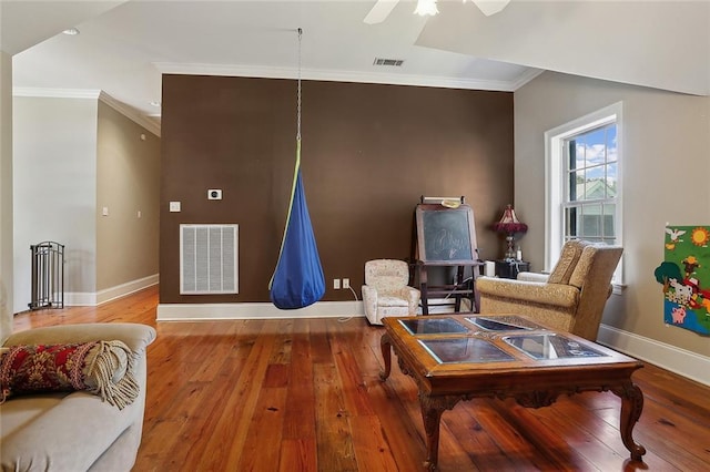 living area with hardwood / wood-style flooring, ornamental molding, and ceiling fan