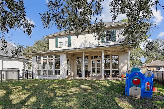 back of property with a lawn and a sunroom