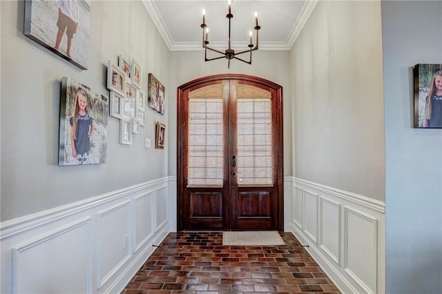 entryway with french doors, crown molding, and a chandelier