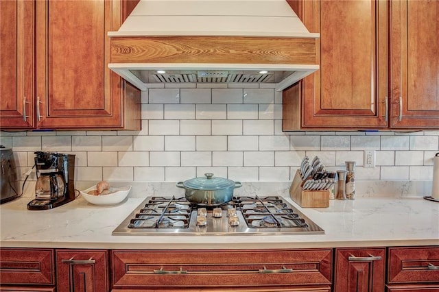 kitchen featuring tasteful backsplash, premium range hood, and stainless steel gas cooktop