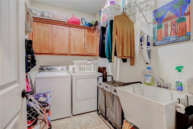 clothes washing area with sink, cabinets, and washer and dryer