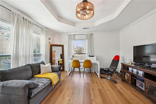 interior space with ornamental molding, light hardwood / wood-style floors, and a tray ceiling