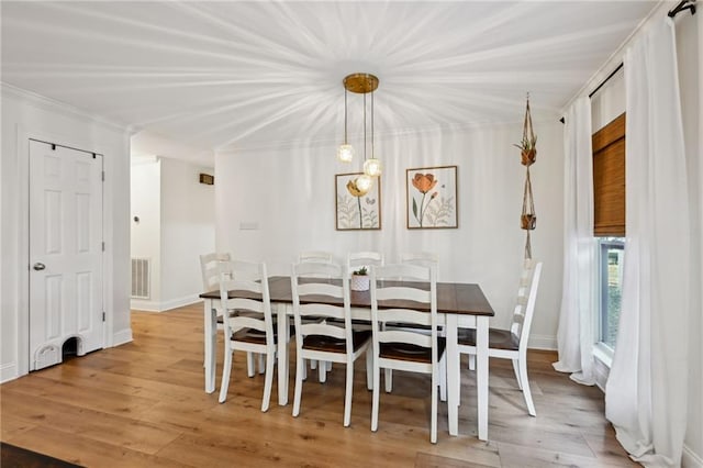 dining area with crown molding and light hardwood / wood-style flooring