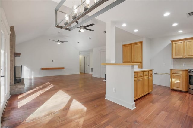 kitchen featuring stainless steel range with electric stovetop, lofted ceiling, light brown cabinets, and light wood-type flooring