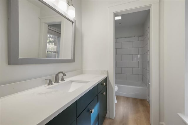 full bathroom featuring vanity, tiled shower / bath, hardwood / wood-style floors, and toilet