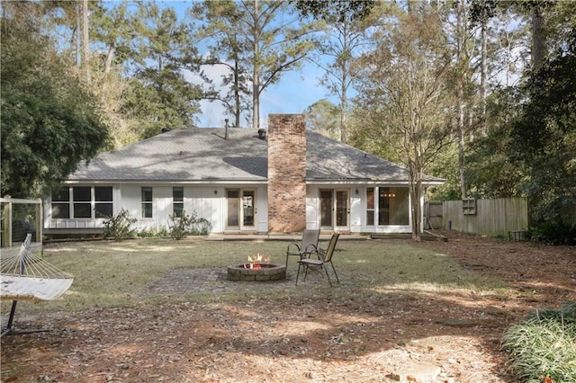 back of property with a lawn, a sunroom, and an outdoor fire pit