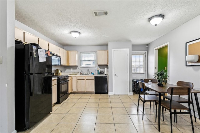 kitchen featuring light brown cabinetry, sink, light tile patterned floors, black appliances, and a textured ceiling