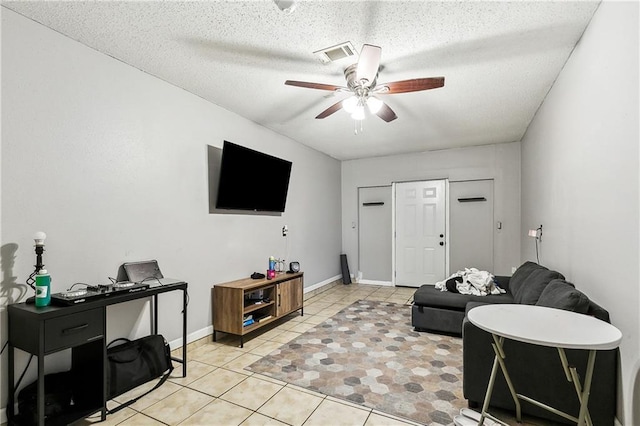 living room featuring light tile patterned flooring, ceiling fan, and a textured ceiling