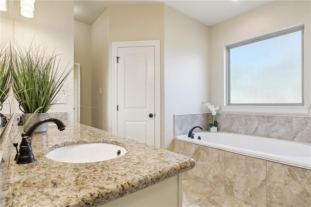 bathroom with vanity and tiled tub