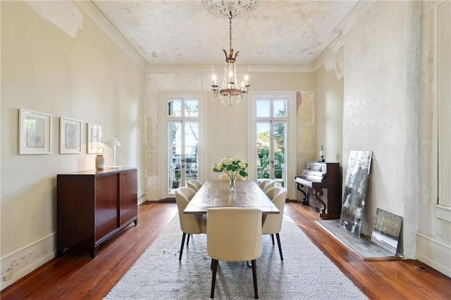 dining area with ornamental molding, dark wood-type flooring, and a notable chandelier