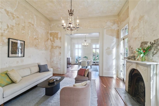 living room with ornamental molding, hardwood / wood-style floors, a notable chandelier, and a fireplace