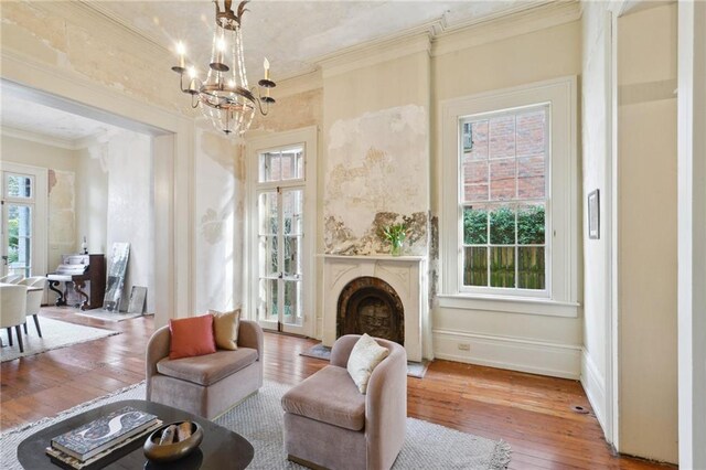 sitting room with hardwood / wood-style flooring, ornamental molding, and a notable chandelier